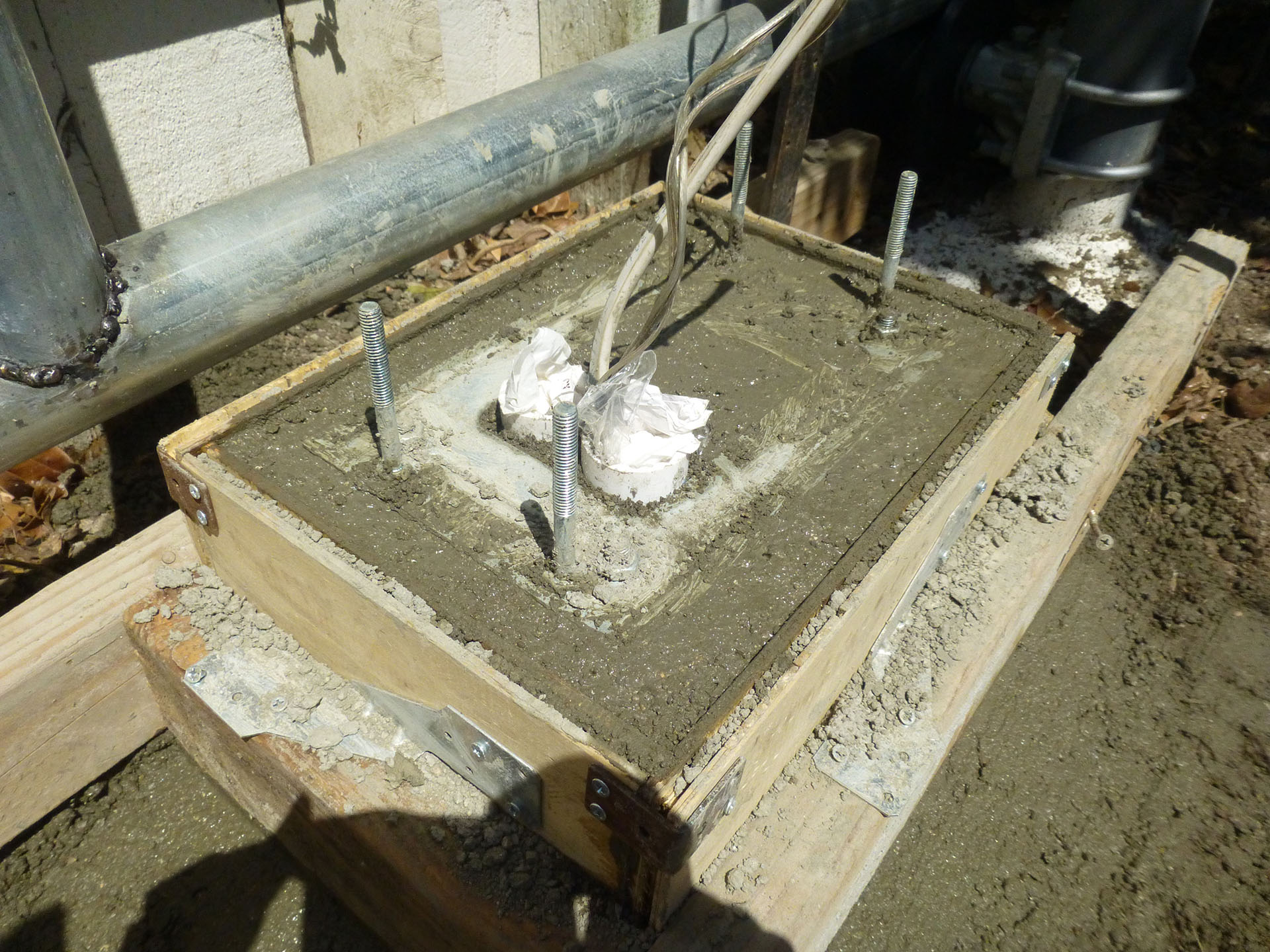 Concrete mix is still wet. Note the mounting bracket is placed on top of the mix with the four anchor bolts buried inside.